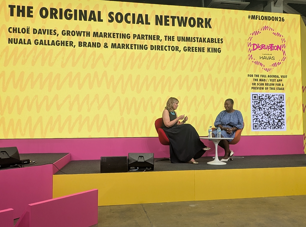 Chloe Davies from the Unmistakables and Nuala Gallagher from Greene King speak on a colorful conference stage before a yellow screen reading THE ORIGINAL SOCIAL NETWORK