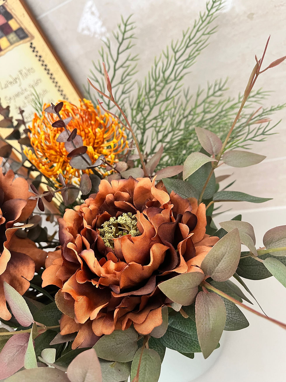 Close up view of burnt orange peonies with greenery