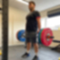 Man lifting a hex bar with weights on each end of the bar.