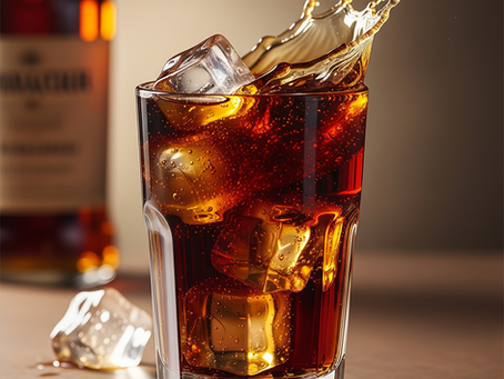 Ein 'Whisky & Cola' Longdrink in einem Glas mit Eiswürfeln und einem spritzenden Effekt.