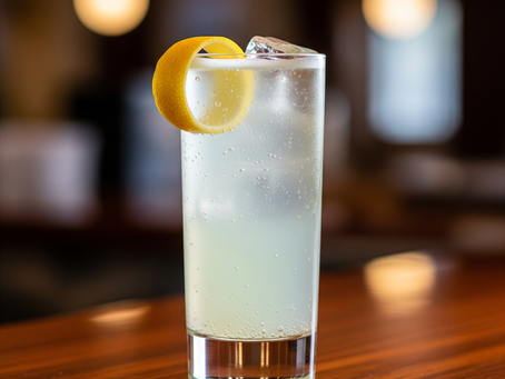 Ein erfrischender Morning Glory Fizz Cocktail in einem Fizz-Glas, garniert mit einer Zitronenzeste, auf einer Holztheke.