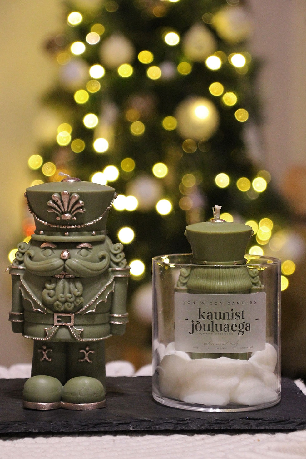Thumbnail: pähklipureja kujuga roheline jõuluküünal kuldsete detailidega jõulukuuse taustal