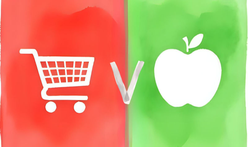 Red shopping cart vs. green apple icons on split background, suggesting a comparison. Red and green sections with a bold "V" in the center.
