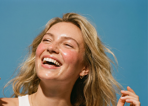 le visage d'une femme blonde souriante et heureuse, derrière elle un beau ciel bleu. Elle se prépare à s'engager dans le programme ELLE de Maman d'Amour