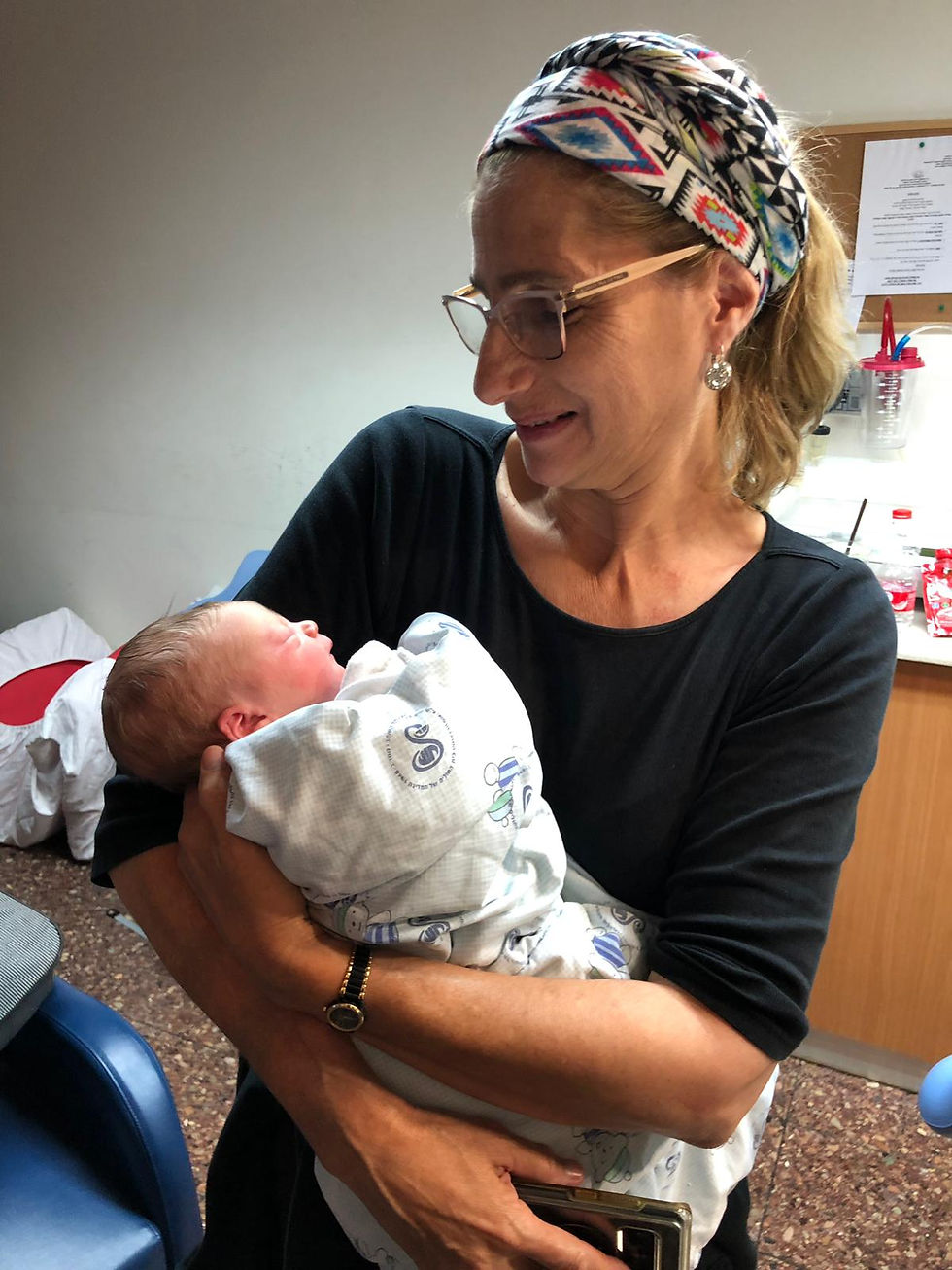 Michal holding a newborn after assisting in the birth