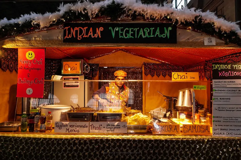 Stan makanan bertuliskan Indian Vegetarian menampilkan berbagai menu kari dan camilan, menawarkan pilihan makanan halal di Swiss bagi pengunjung pasar malam.
