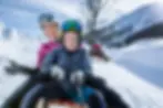 A family with happy faces riding toboggan in Switzerland