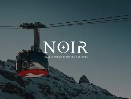A red cable car cabin with a white Swiss cross travels above snow-covered mountain slopes under a darkening sky.