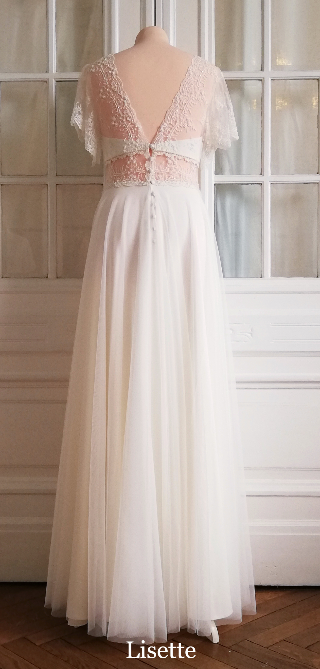 Brautkleid aus weichem Tüll über fließender Viskose, Oberteil mit nostalgischer Spitze und flatternden Ärmeln, Taille transparent.