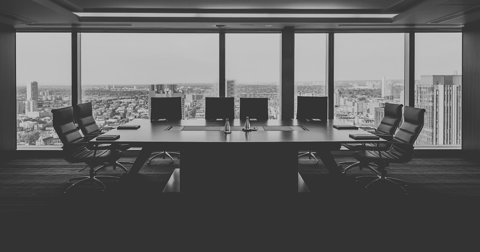Empty modern conference room with black chairs and long table beside floor-to-ceiling windows overlooking a city skyline