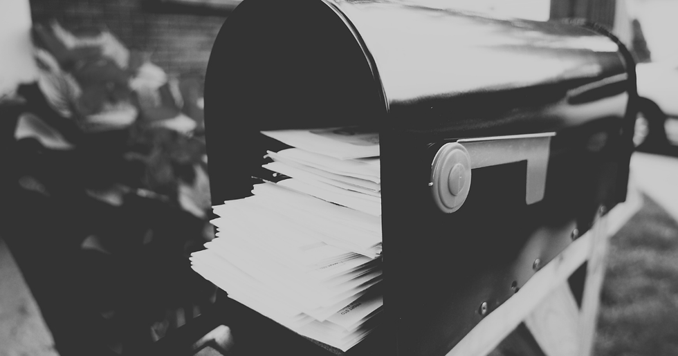 Black-and-white close-up of an overflowing mailbox stuffed with stacked letters.