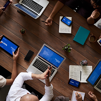 A top down photo a person using a laptop on a dark wood desk.