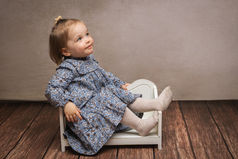 Séance photo enfant en studio avec fauteuil miniature, pose naturelle.