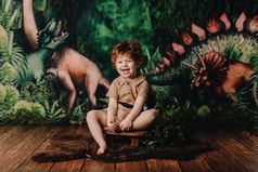 Séance bambin originale thème dinosaure, enfant heureux dans un décor immersif.