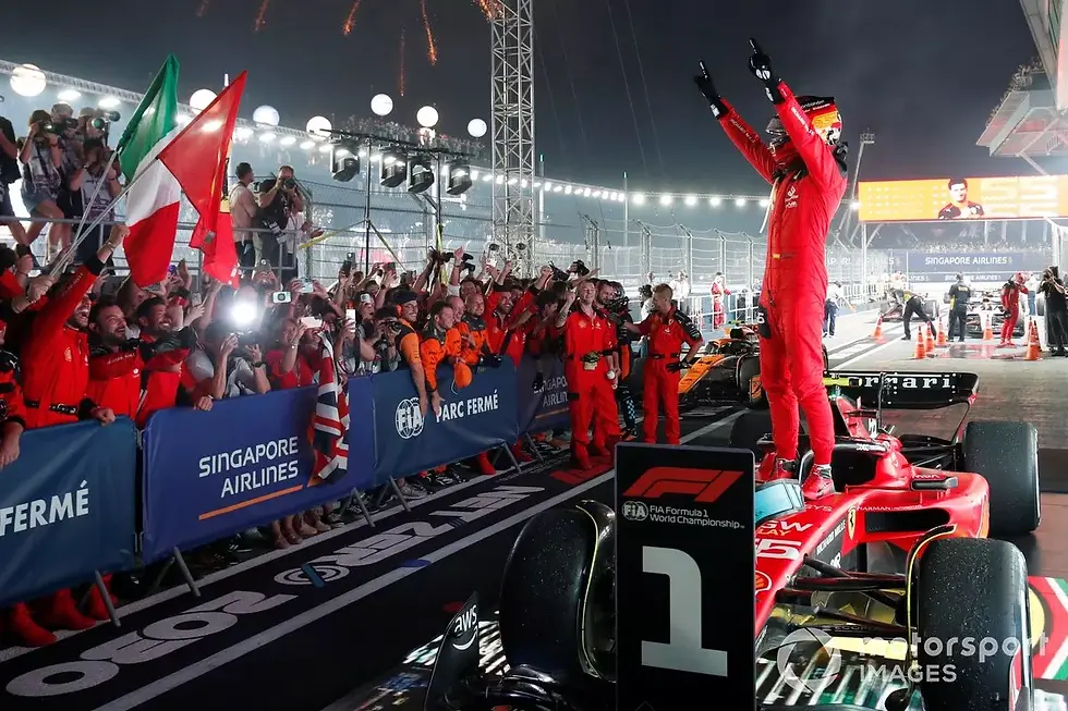 Carlos Sainz stands ontop of his car after winning the 2023 Singapore GP