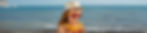 Child in a straw hat and red sunglasses puts on sunlotion. Ocean waves in the background, sunny and joyful mood.