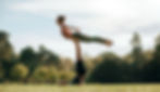 Two young people doing advanced yoga pose at the park