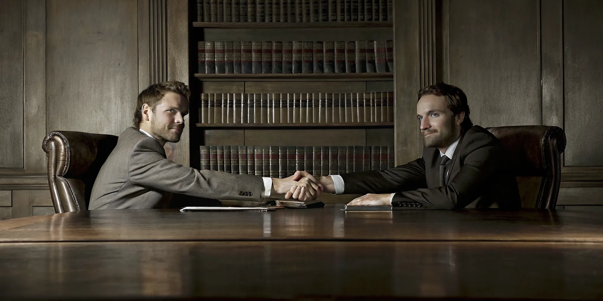 Two attorneys shaking hands in a wood-paneled Arkansas law office representing a co-counsel partnership