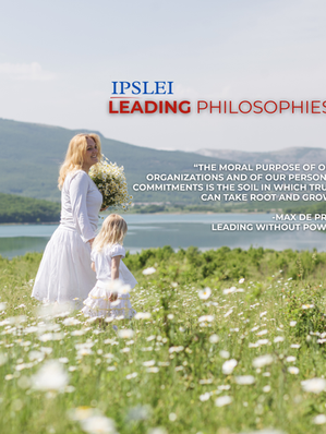 Blonde woman and small child both wearing white dresses, walking through a field of daisies near a lake.