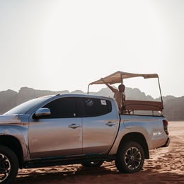 • The Wadi Rum desert landscape boasts mountains and dunes.
• Family exploring the desert terrain in Wadi Rum.
• Dune climbing in Wadi Rum, Jordan.
• Rocky Mountain formations rising above the desert floor.
• Wadi Rum offers a wide panoramic view of its desert landscape.
• A hot air balloon is flying over Wadi Rum at sunrise.
• Aerial view of desert dunes and mountains from above.
• Sun City Camp tents set against the Wadi Rum desert.
• The exterior of Sun City Camp is located in Wadi Rum.
• Evening light over the Wadi Rum desert.
• Night sky filled with stars above Wadi Rum camp.
• Campfire setup under the desert sky in Wadi Rum.
• Desert adventure vehicle driving through Wadi Rum.
• Scenic viewpoint overlooking the vast Wadi Rum valley.
• Sunset colors across the Wadi Rum landscape.