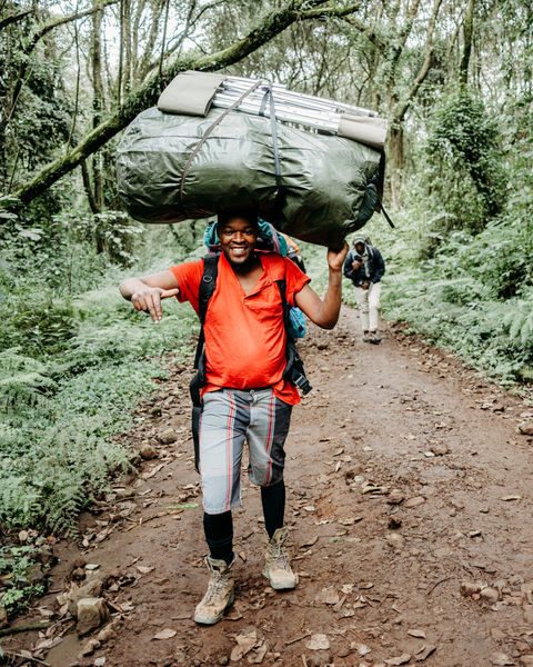 Man carrying large backpack walking on a trail in a lush forest