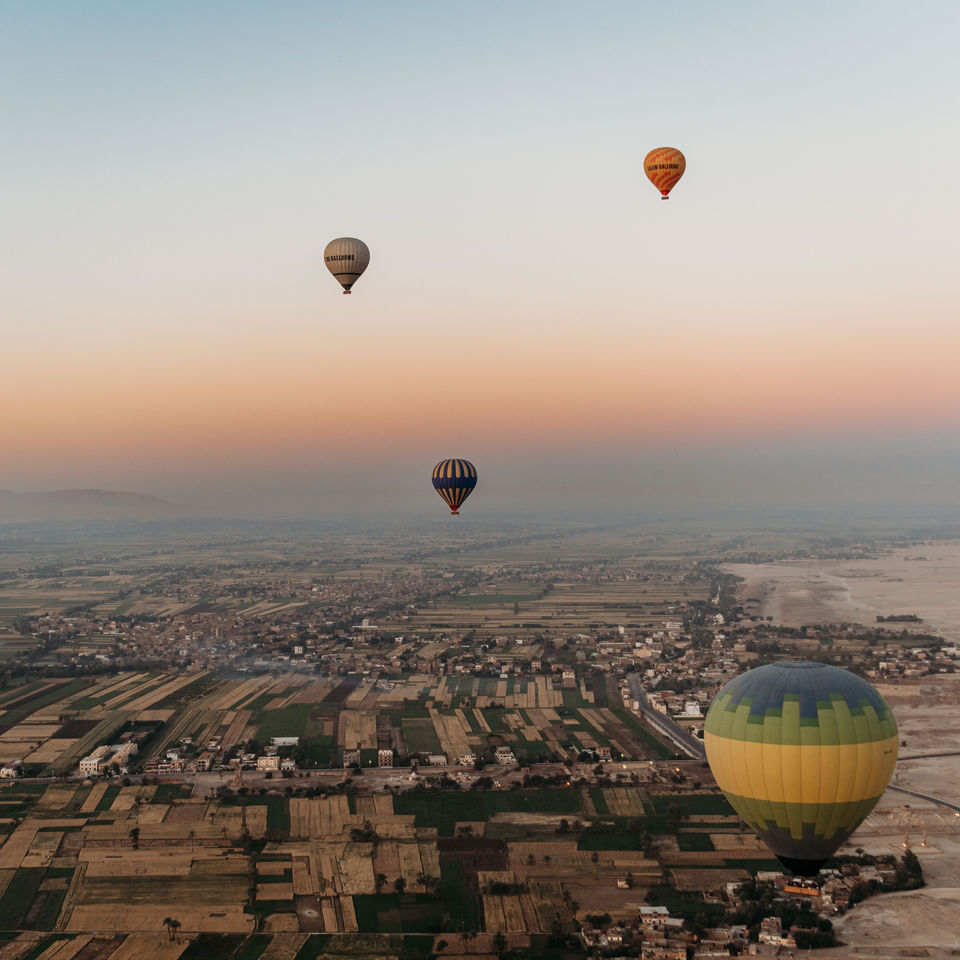 Balloon & Aerial Views:
• Hot air balloon flying over Luxor at sunrise.
• Aerial view of the Valley of the Kings from a balloon.
• Balloon drifting above the Nile River and farmlands.
• Sunrise light over Luxor’s desert and green fields.
• Wide shot of multiple balloons rising over Luxor.

Landmarks From Above:
• Aerial view of the Temple of Hatshepsut from the balloon.
• Desert landscape near the Valley of the Kings from above.
• Balloon view overlooking ancient tomb areas in Luxor.
• Scenic aerial shot of Luxor’s West Bank at sunrise.
• View of Luxor city from a hot air balloon.

Experience & Atmosphere:
• We were inside the hot air balloon basket during the sunrise flight.
• Burners lighting up inside the balloon before takeoff.
• Passenger looking out over Luxor from the balloon.
• Balloon shadow cast over the fields of Luxor.
• Balloon landing area in the Luxor desert.
