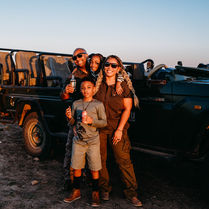 • Family on safari vehicle at Tau Game Lodge in Madikwe.
• Guide Silas is leading a game drive in the Madikwe Game Reserve.
• Wildlife sighting during safari at Madikwe, South Africa.
• Elephants gathering near the waterhole at Tau Game Lodge.
• Sunset view over Madikwe Game Reserve.
• Tau Game Lodge's exterior overlooks the landscape.
• A safari vehicle is driving through 76,000 acres of Madikwe terrain.
• Close-up of animals spotted during our safari.
• The family is enjoying a VIP safari experience in South Africa.
• The Madikwe landscape was captured during the sunrise game drive.