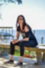 A woman sitting on a bench near the ocean on a sunny day