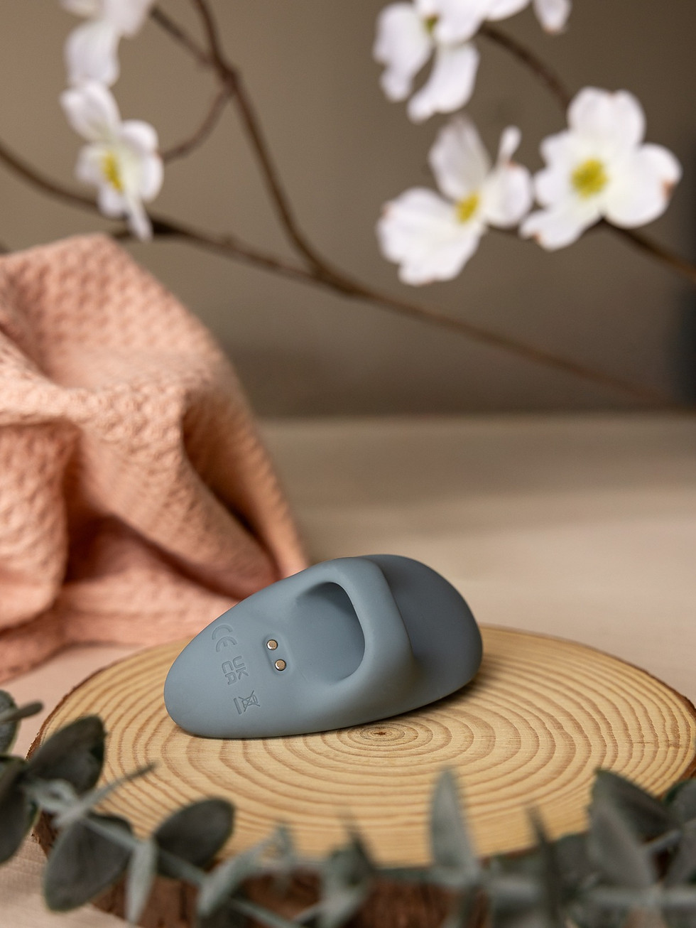 Grey Viola finger vibrator on wood with light pink fabric and white flowers