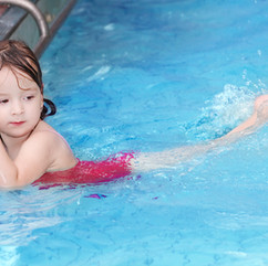 Girl holding wall and kicking in a pool