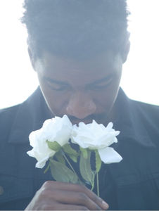 Homme en costume tenant une rose blanche devant son visage, illustrant le deuil et la perte d'un être cher