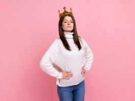 Femme portant une couronne en carton sur fond rose, illustrant le masque du narcissisme et la fausse confiance en soi