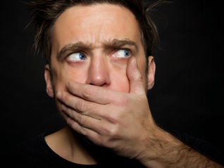 Homme se couvrant la bouche, illustrant la difficulté des hommes à exprimer leurs émotions et consulter un thérapeute