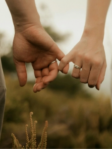 Couple se tenant par le petit doigt, symbolisant le lien fragile et la reconnexion dans la thérapie de couple