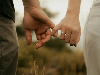 Couple se tenant par le petit doigt, symbolisant le lien fragile et la reconnexion dans la thérapie de couple