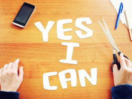 Mains écrivant YES I CAN sur une table avec un téléphone et des stylos, illustrant la confiance en soi et les empreintes émotionnelles