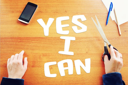 Mains écrivant YES I CAN sur une table avec un téléphone et des stylos, illustrant la confiance en soi et les empreintes émotionnelles