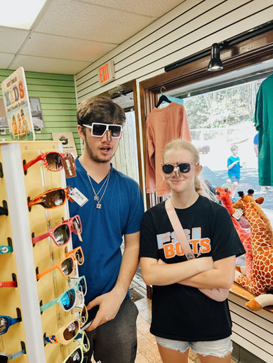 Two teens trying on sunglasses at a gift shop