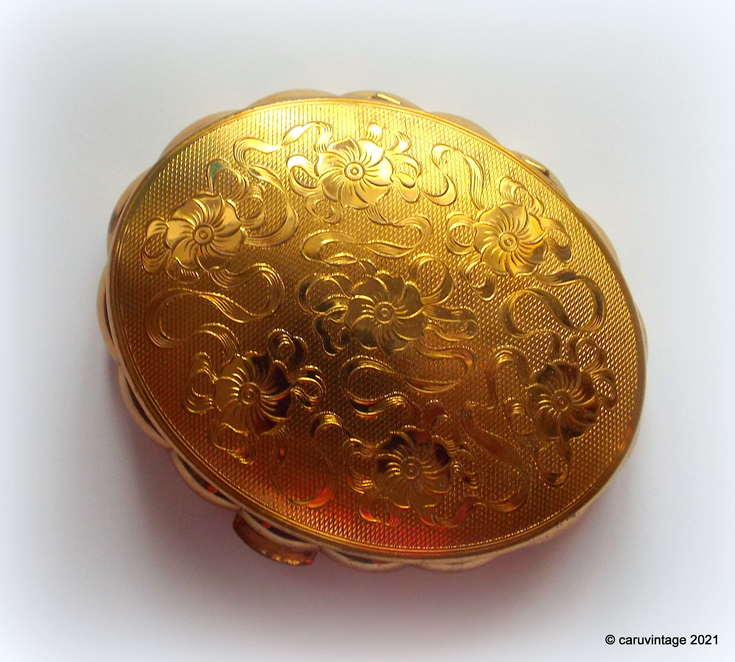 Kigu gold coloured oval scalloped powder compact in very good condition