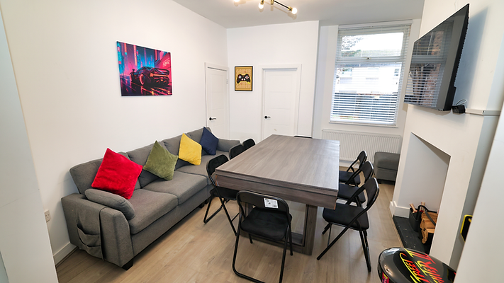 Modern living room with gray sofa, colorful cushions, dining table, wall art.