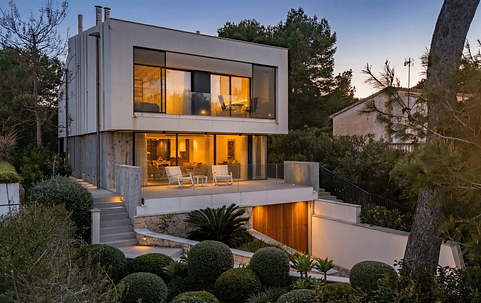 Modern two-story house with illuminated glass windows at dusk.