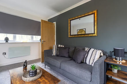 Modern serviced accommodation bedroom featuring a king bed, work desk with monitor, and floor-to-ceiling windows overlooking