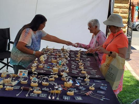 Santa Fe New Mexico Native American jewelry artist Evelyn Frank Chee selling handcrafted sterling silver jewelry at an outdoor art market.