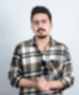 Porträt eines bärtigen Mannes mit Brille, der an einer weißen Wand steht