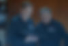 Zwei SPS-Mitarbeiter in dunklen Hemden stehen vor einem offenen Schaltschrank und prüfen Dokumente. Die Umgebung wirkt technisch und konzentriert.
