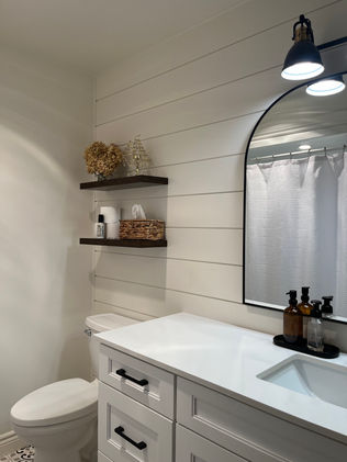 Farmhouse bathroom with shiplap wall, wood shelving, black accents