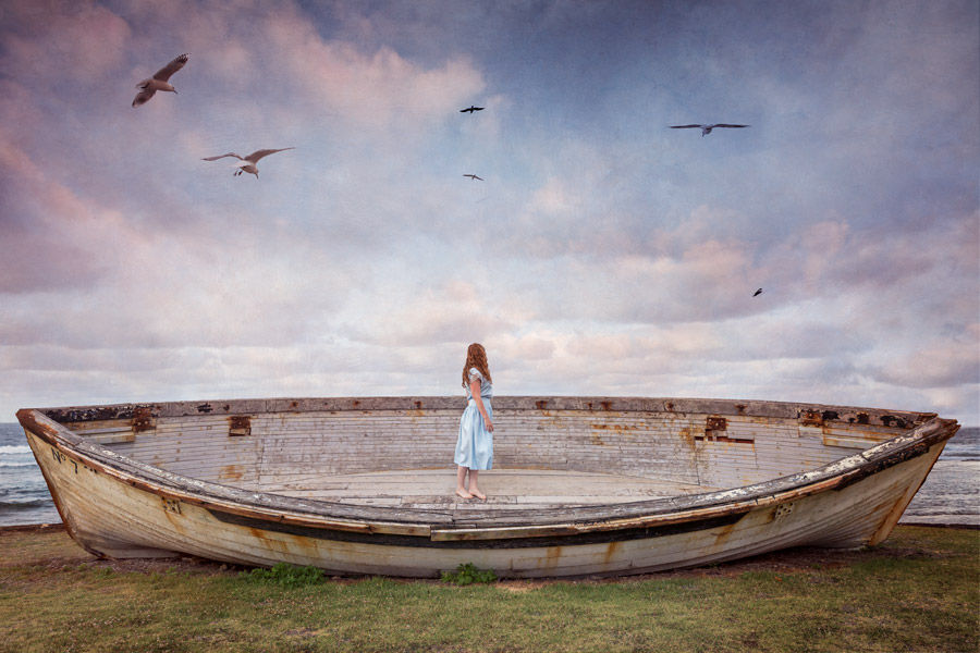 A Ship in Harbor is Safe, a conceptual photograph of a girl standing in a large boat on land staring out to sea