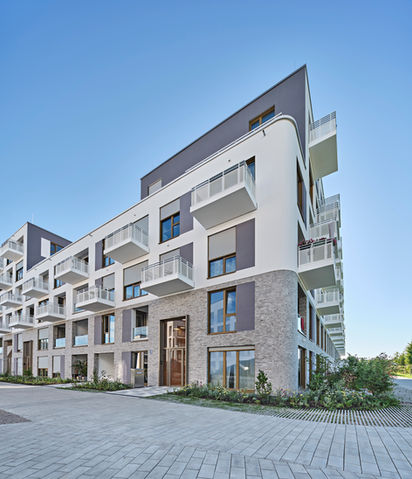 Perspektivische Außenansicht eines modernen, mehrstöckigen Wohnkomplexes mit weißen Balkonen.