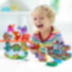 A happy child playing with the wooden dinosaur and car balancing stacking toys.