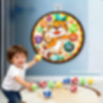 A young boy reaches for a circular tiger-themed fabric dart board hanging securely on a blue bedroom wall.